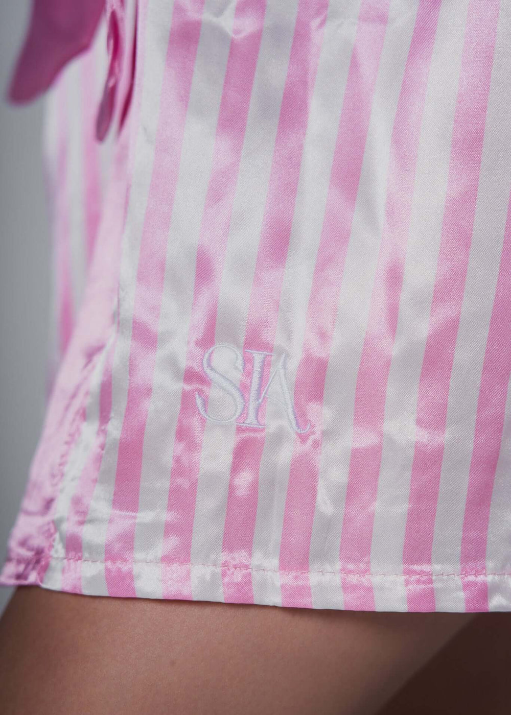 Pantalon scurt satin roz cu dungi albe și logo SIA Homewear pe margine.
