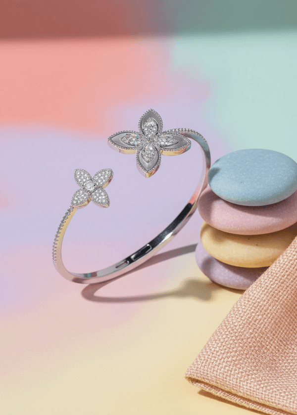 Set SIA Floral Embrace, brățară deschisă argintie cu cristale în formă de flori, prezentată pe fundal pastel elegant