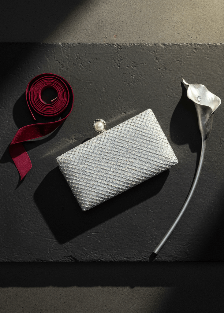 Clutch Crystal Pearl argintiu cu cristale și închidere cu perlă, accesoriu de seară elegant pe fundal gri cu panglică roșie