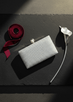 Clutch Crystal Pearl argintiu cu cristale și închidere cu perlă, accesoriu de seară elegant pe fundal gri cu panglică roșie