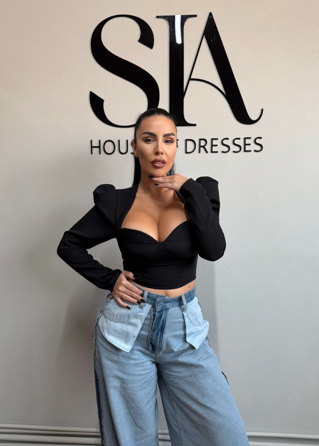 Top AURA din stofă elastică, croială tip corset cu push-up natural, purtat cu jeanși largi, fundal logo SIA House of Dresses