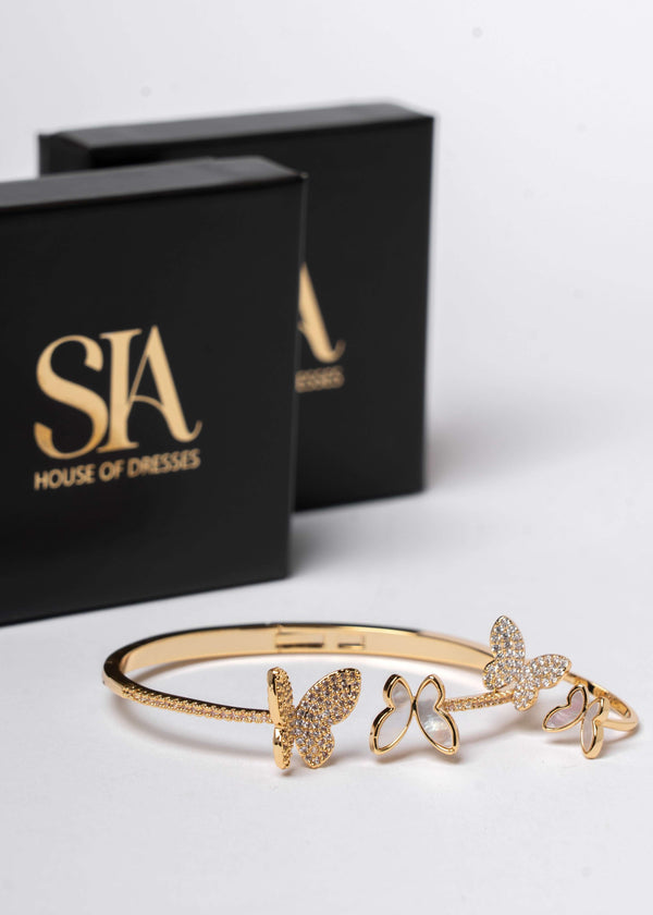 Set SIA Butterfly Dream, brățară aurie cu fluturi și cristale, bijuterie elegantă lângă cutii negre SIA House of Dresses