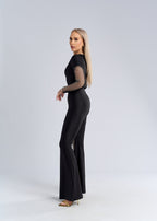 Salopetă neagră din lycra cu inserții din plasă strălucitoare, croială mulată și pantaloni evazați, vedere laterală pe model
