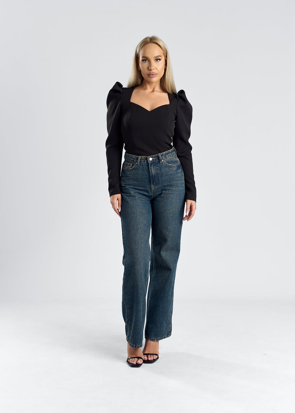 Top cu umeri supradimensionați și decolteu elegant, purtat de o femeie cu jeans în imagine.