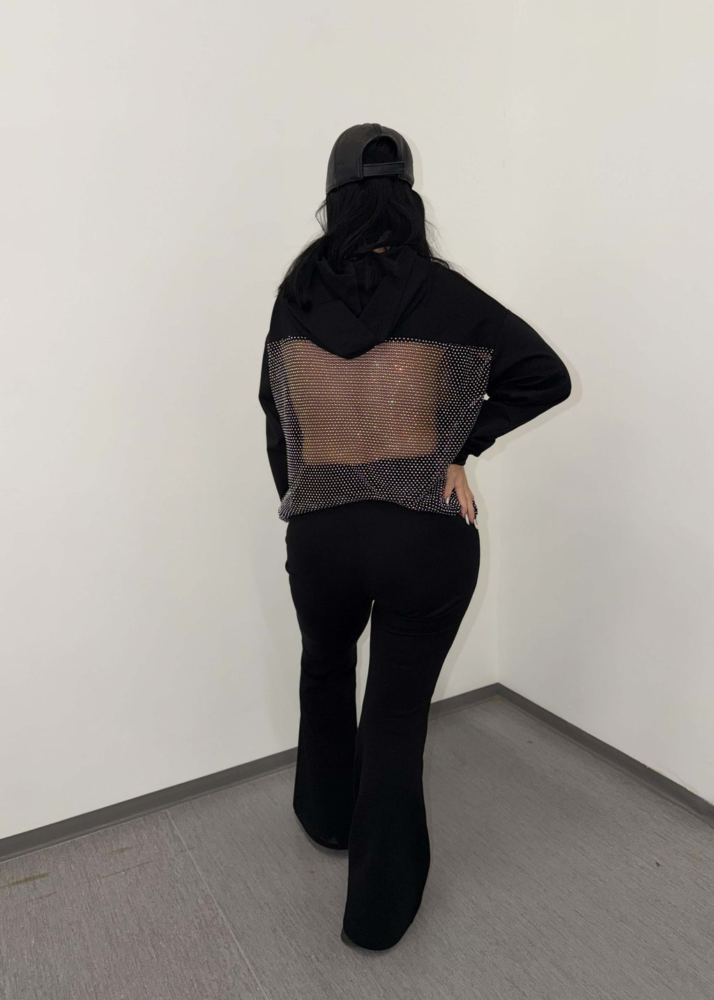 Model purtând SIA Pantaloni tip trening evazați "FLARE" cu partea din spate vizibilă, pantaloni negri confortabili și moderni.