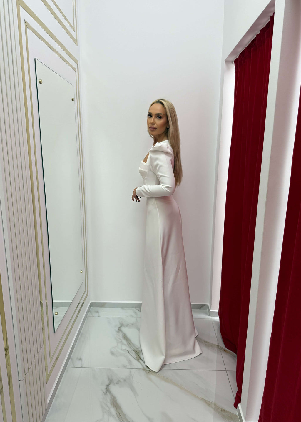 Model îmbrăcată în Set Aura – Top Aura + Wide Pants, demonstrând eleganța și rafinamentul ținutei într-o cabină de probă modernă.