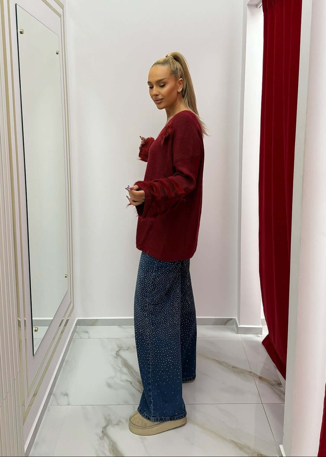 Pulover oversized cu pene SIA Feather Luxe, model poartă Pulover roșu elegant asortat cu pantaloni largi, vedere laterală în cabina de probă
