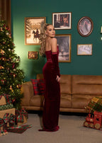 Model purtând SIA Velvet Obsession, rochie lungă din catifea cu mănuși, în fața unui brad de Crăciun și decor festiv.