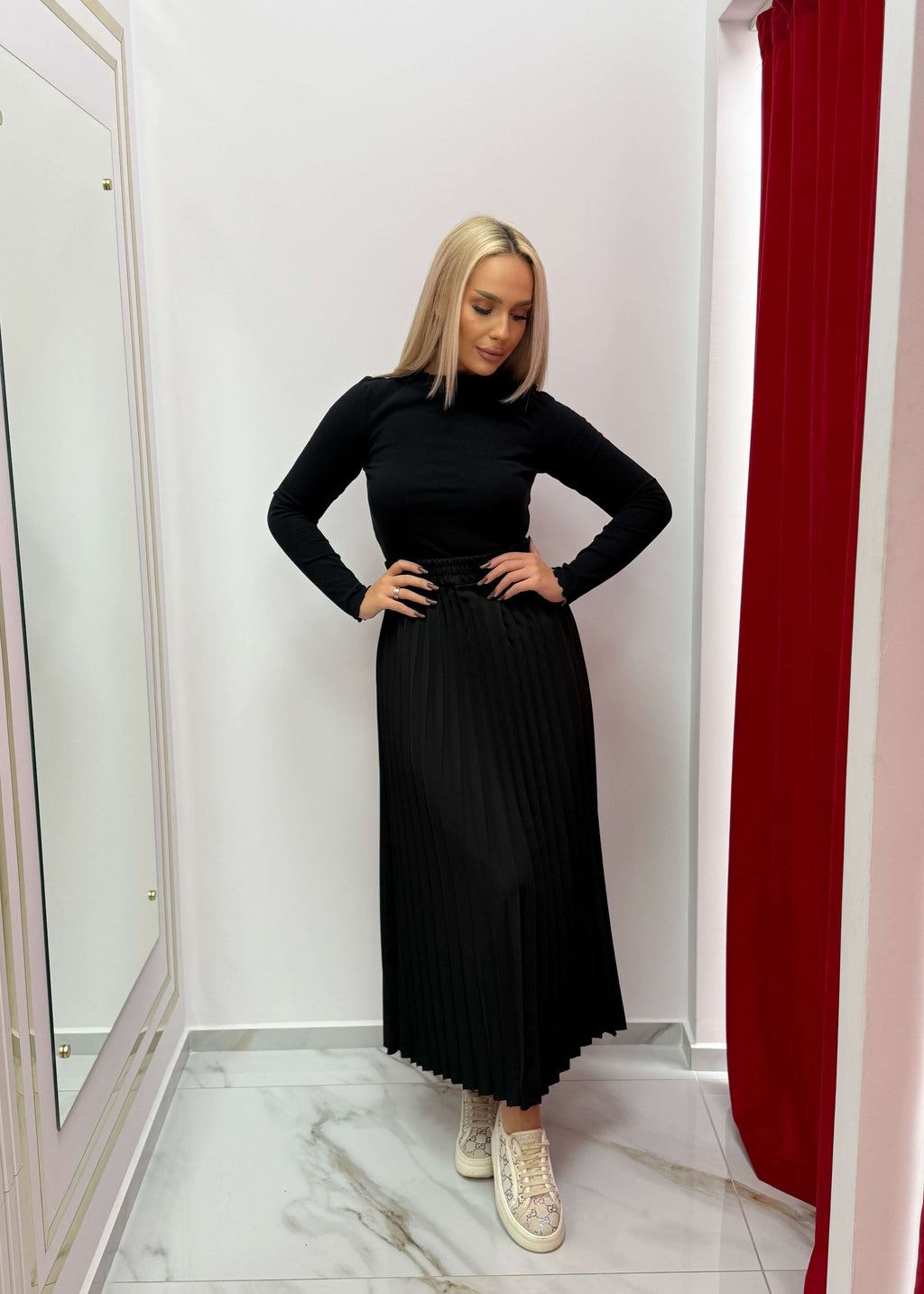 Model poartă fustă midi plisată "URBAN SKIRT" în negru, într-un decor elegant.