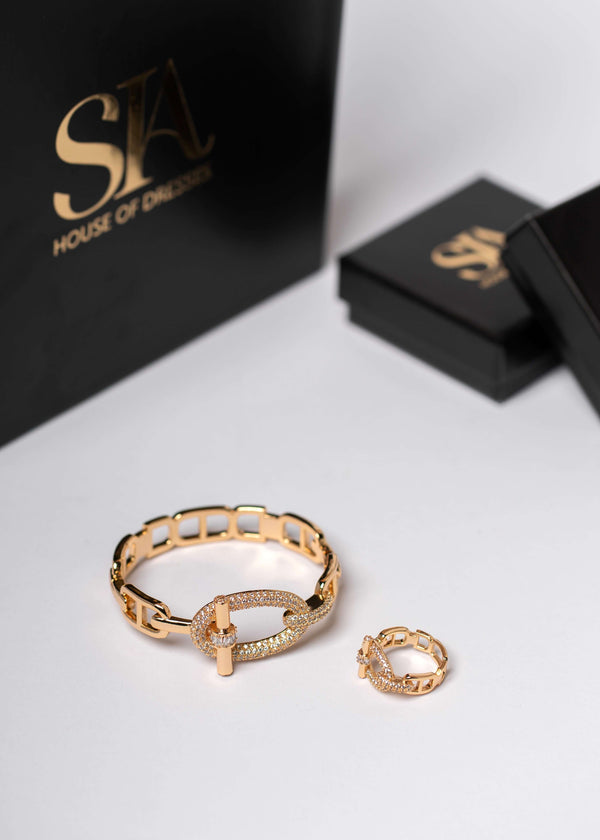 Set SIA Urban Icon cu brățară și inel aurii cu cristale, bijuterii elegante lângă cutii negre de lux