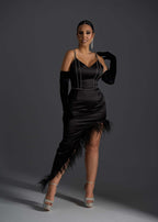 Rochie SIA Femme Fatale asimetrică neagră cu bretele subțiri, strasuri și pene, purtată de model pe fundal gri închis